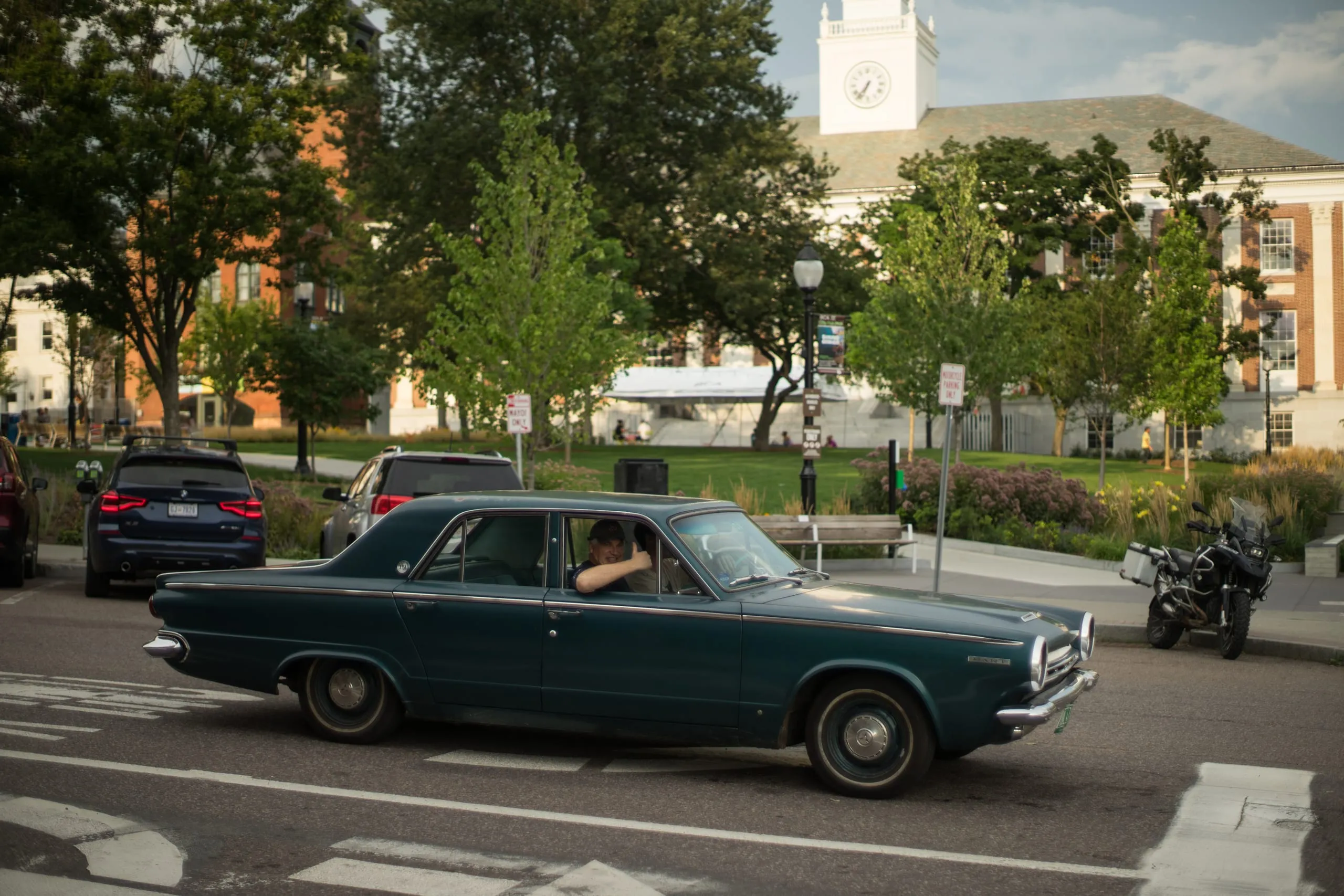 Driver giving a thumbs-up from a 1964 Dodge Dart parked on a Vermont town green