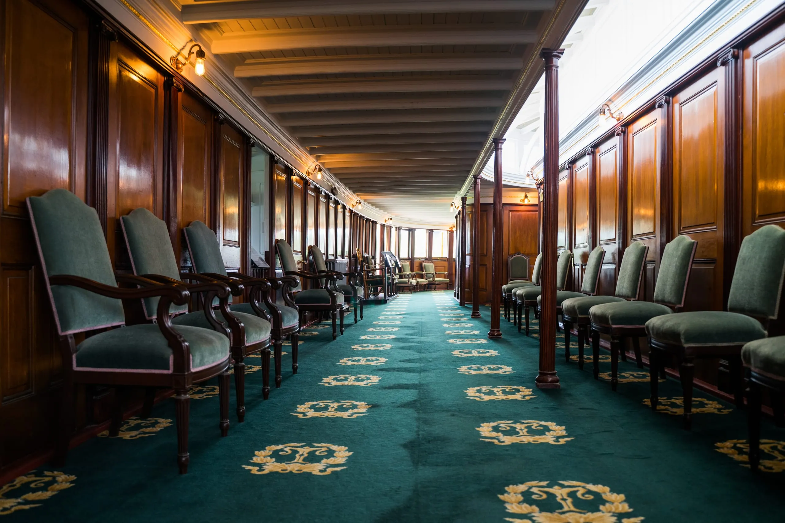 A curved wood-paneled ship's lounge lined with green velvet chairs and a gold-medallion carpet in Vermont.