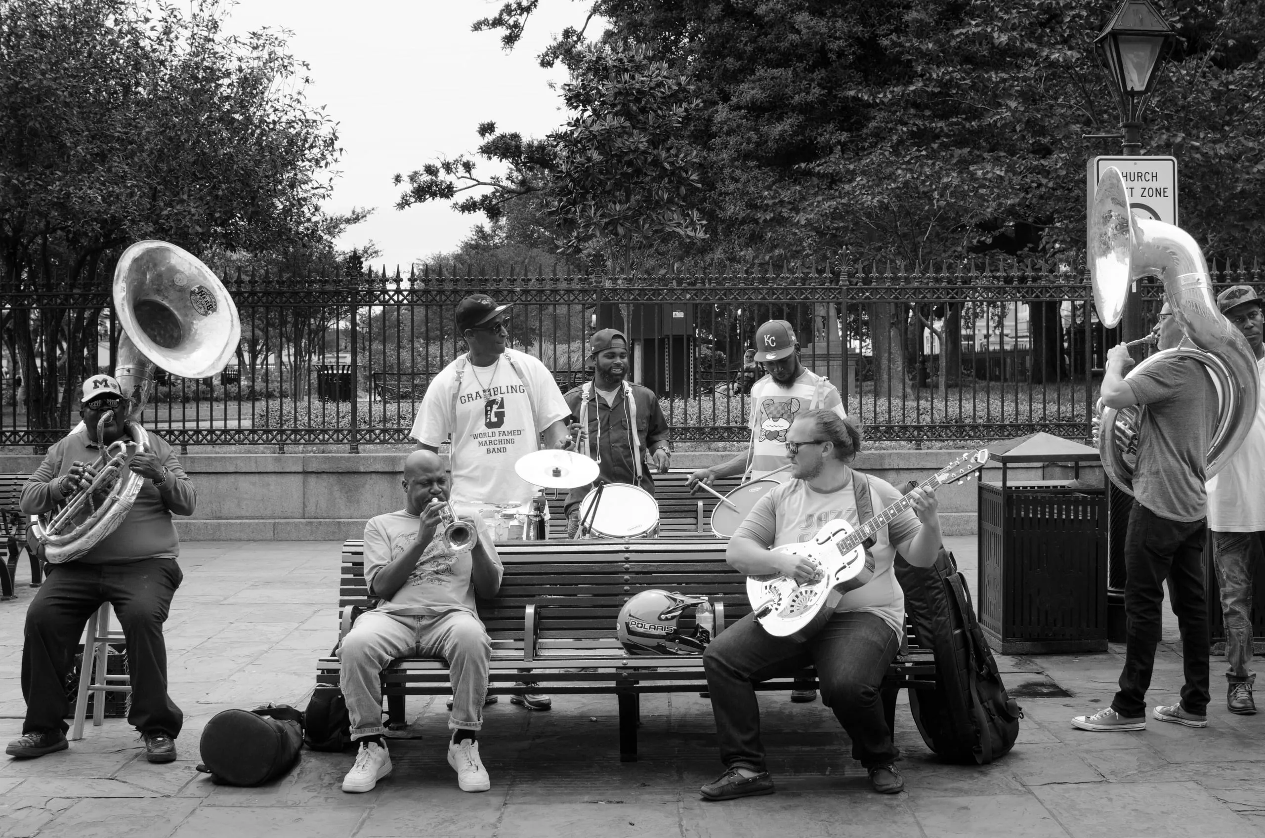 Black and white photograph of a brass band resting on a bench in New Orleans