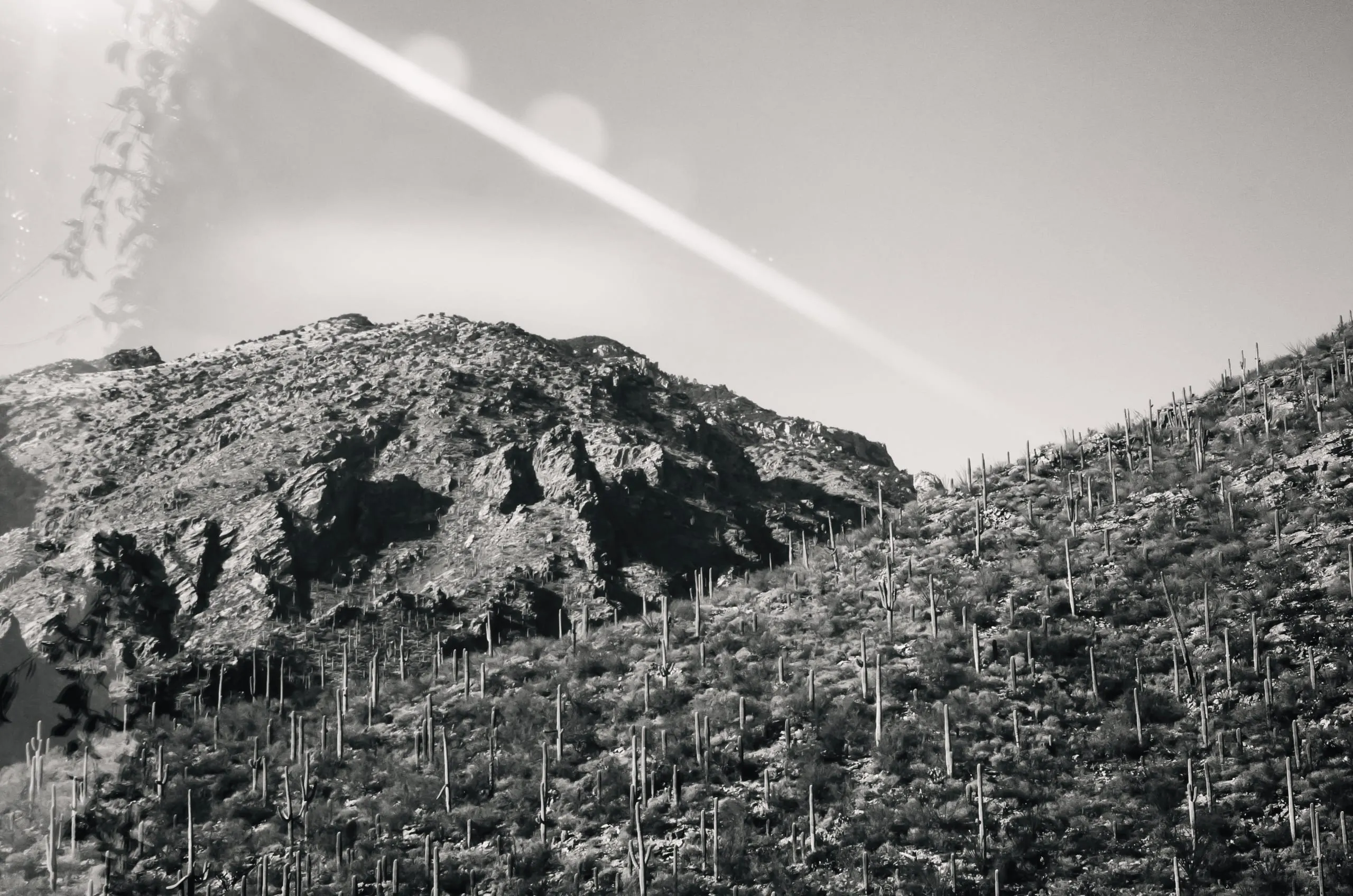 Two contrails crossing in a black and white desert sky