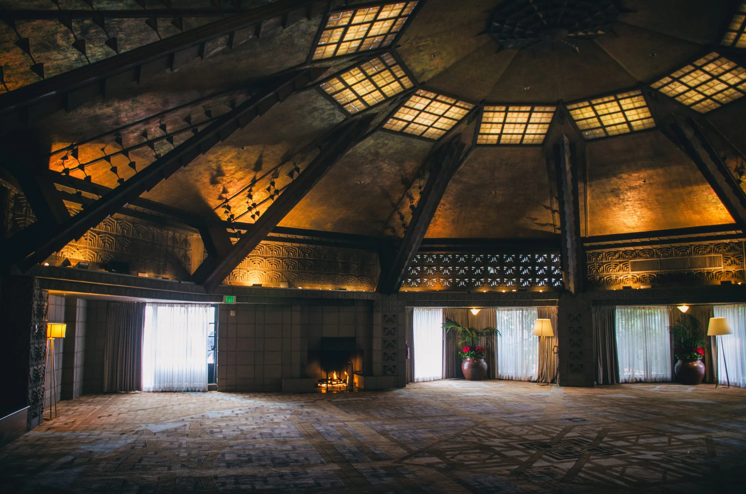 The interior of an ornate domed Art Deco ballroom in Arizona, with skylights, a lit fireplace, floor lamps, and patterned carpet.