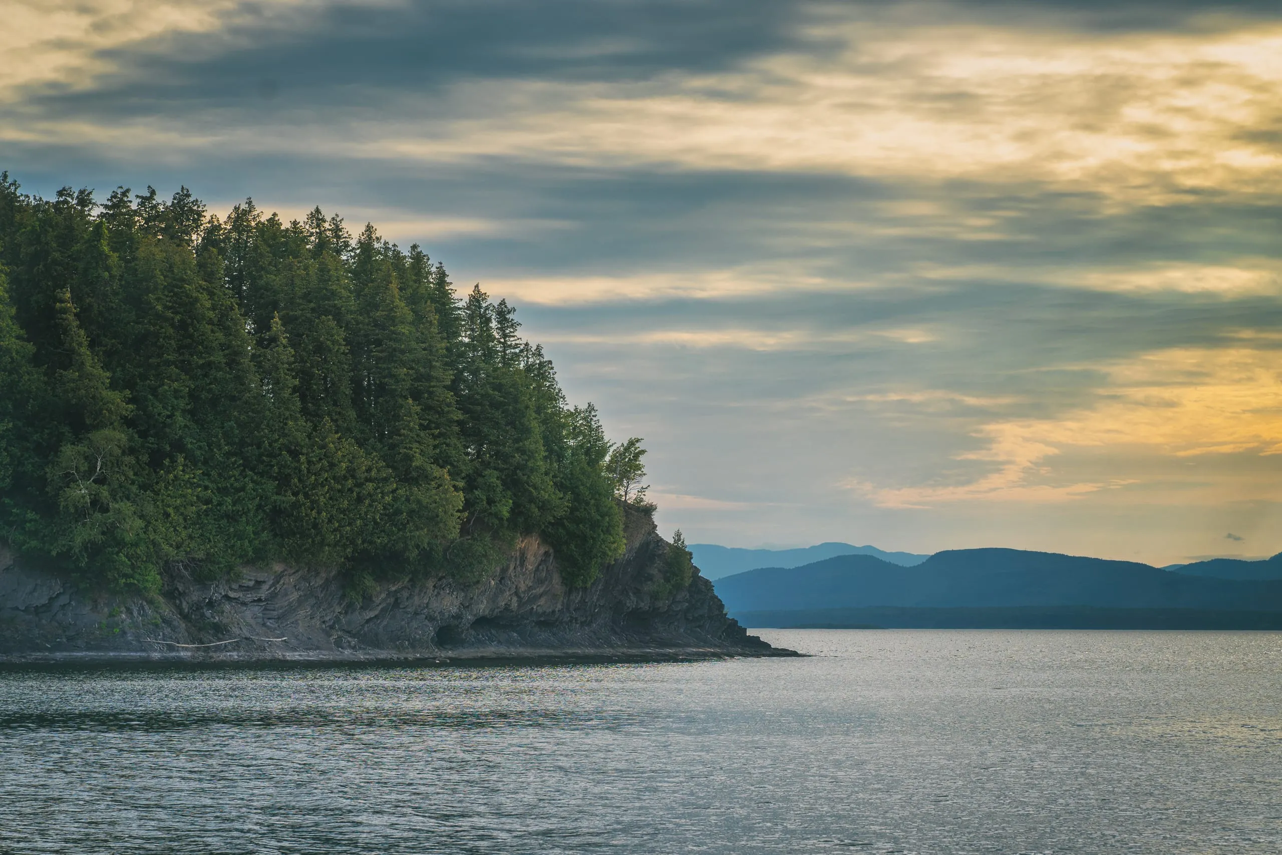 Forested headland silhouetted at dusk over Lake Champlain, Vermont