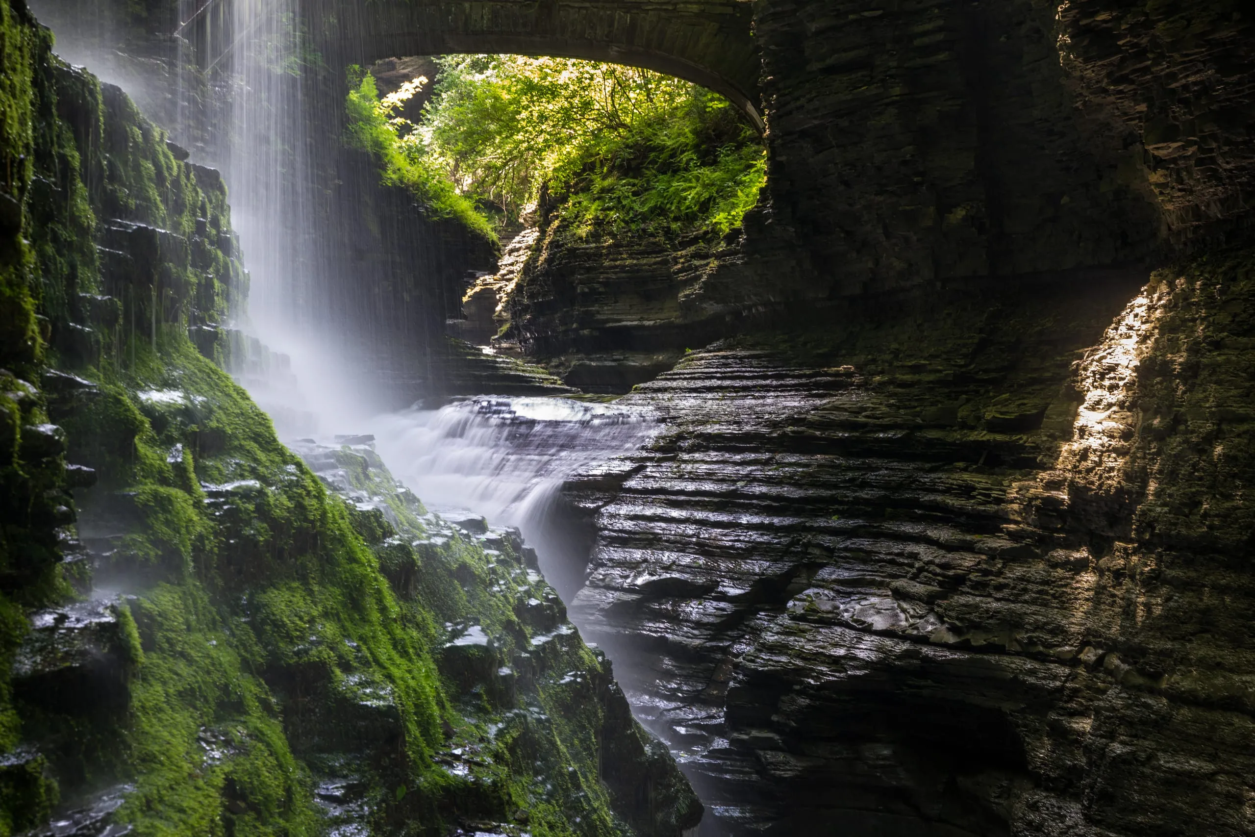 Waterfall seen beneath a natural rock arch in Watkins Glen gorge, New York