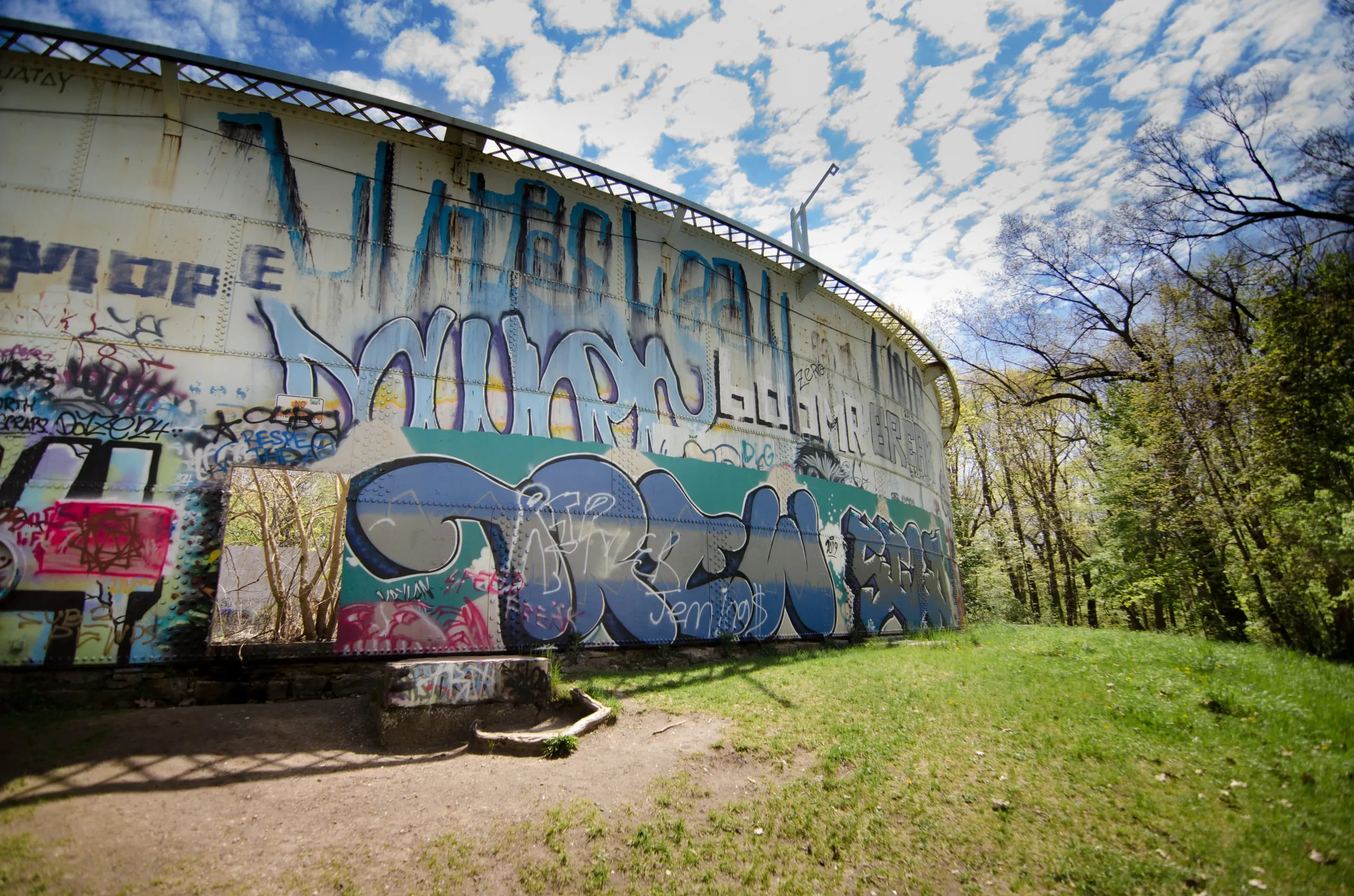 Graffiti-covered curved reservoir tank under a blue sky near Rochester