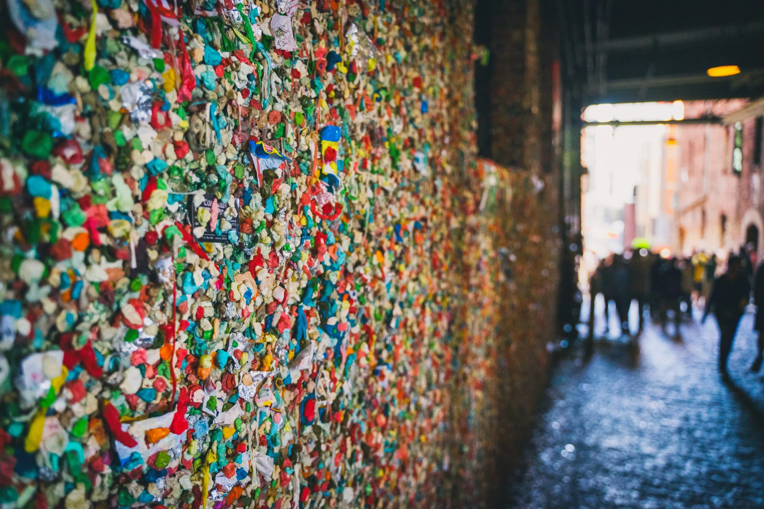 Visitors silhouetted in Post Alley beside Seattle's gum-covered walls