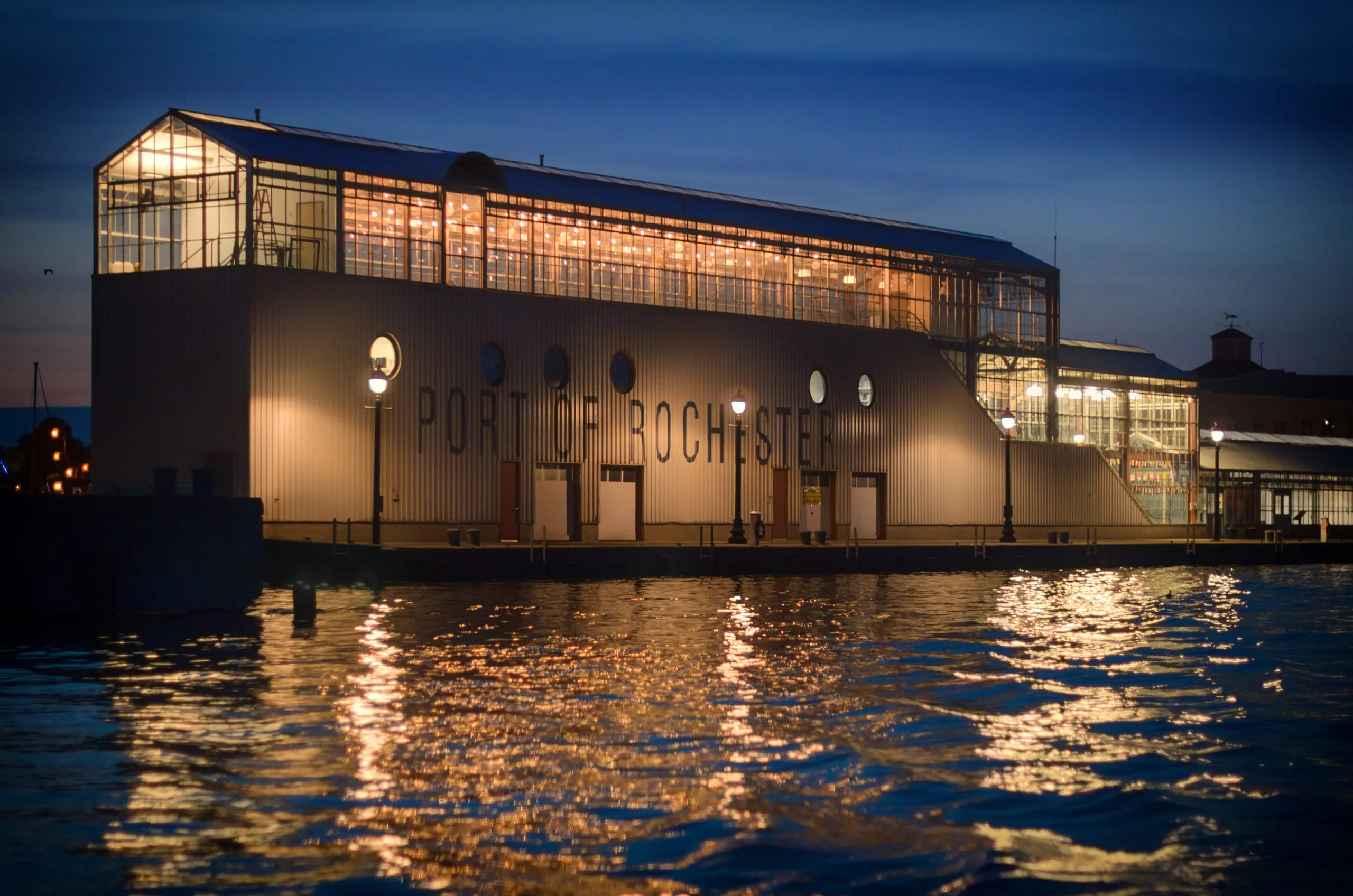 Glass port building glowing at dusk on the Lake Ontario shore, Rochester