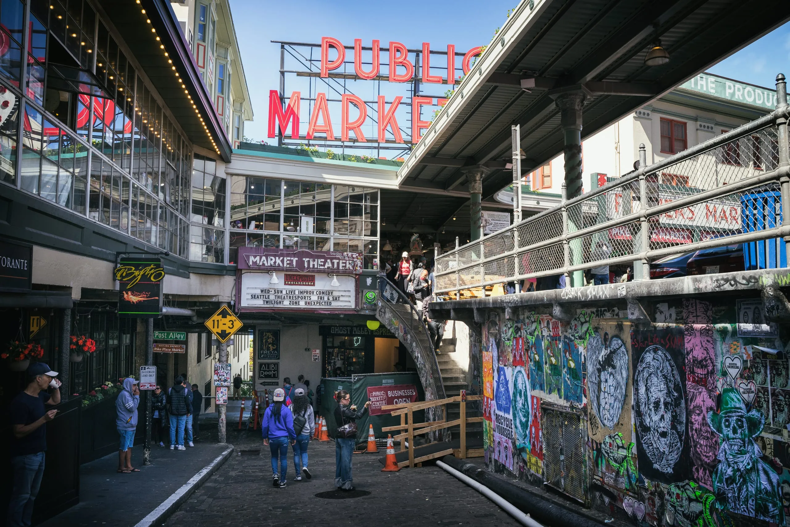 Public Market neon sign glowing above a graffiti-lined alley in Seattle