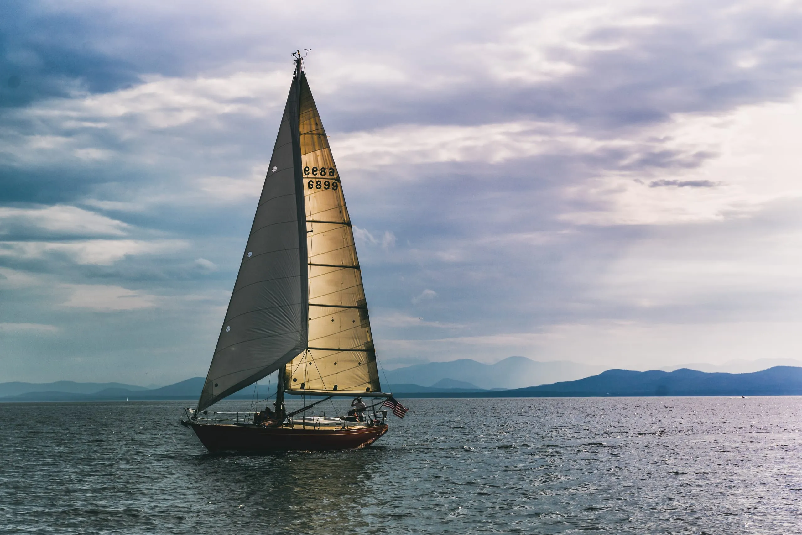 Sailboat crossing Lake Champlain under a dramatic layered sky