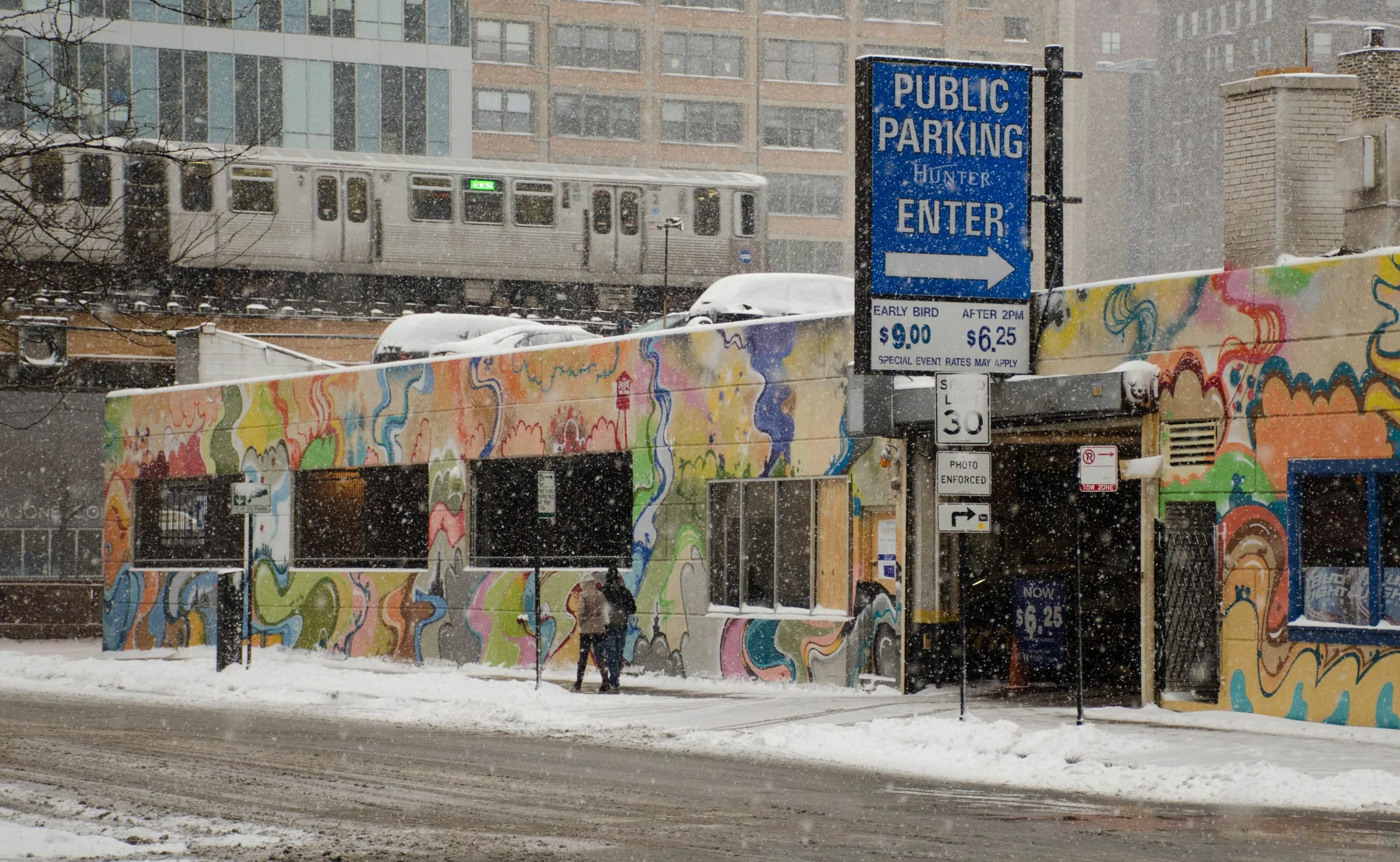 Snow-covered graffiti wall beneath elevated train tracks in Chicago
