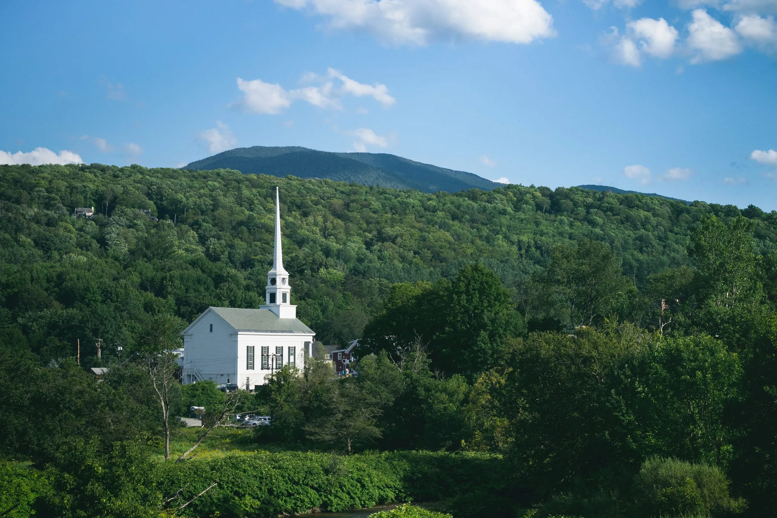 White church steeple of Stowe, Vermont against green hills