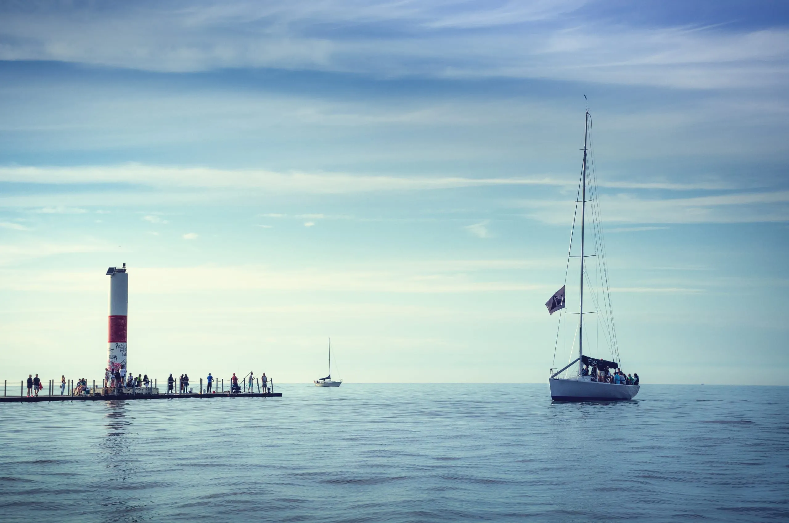 Two lighthouses and distant sailboats on Lake Ontario in minimal pastel light