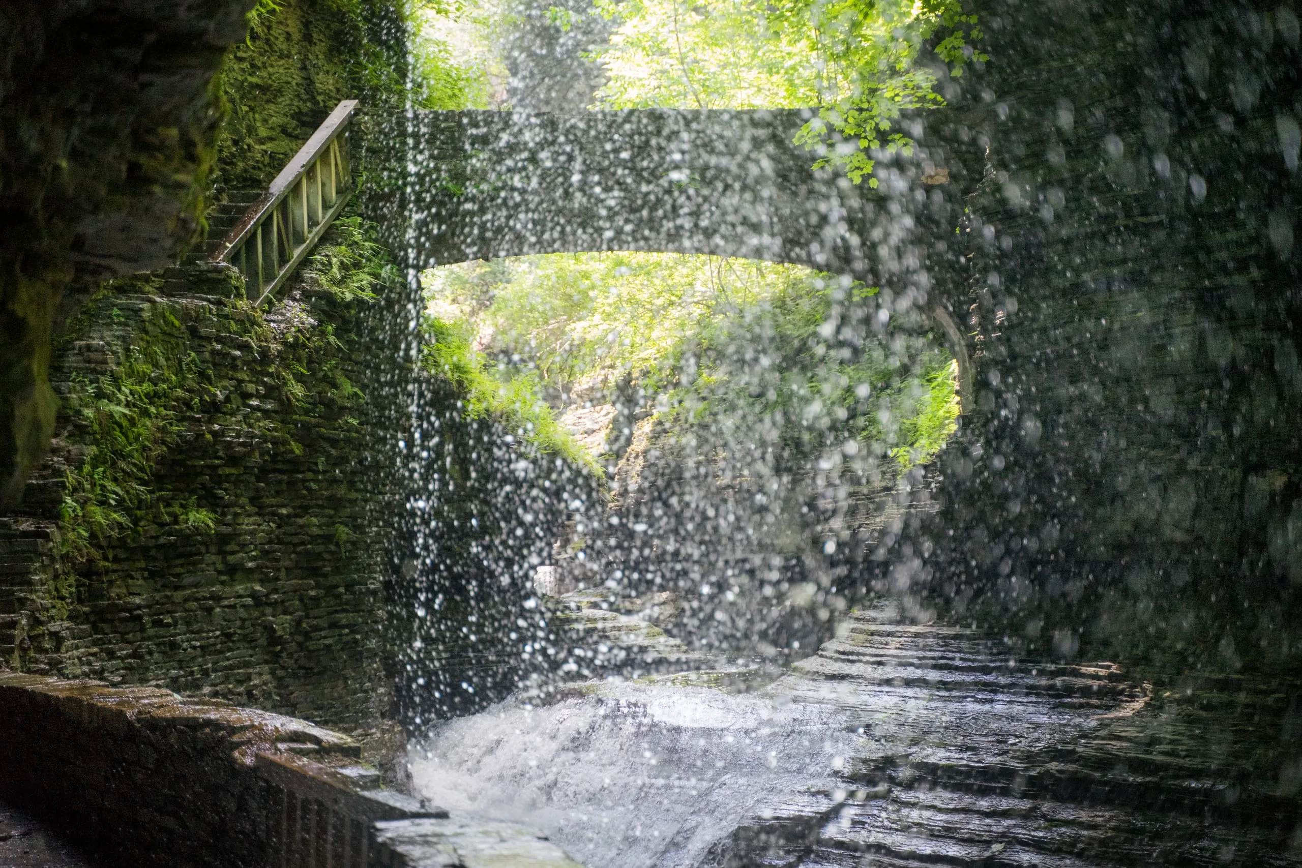 Thin veil cascade falling beside a stone arch bridge in Watkins Glen