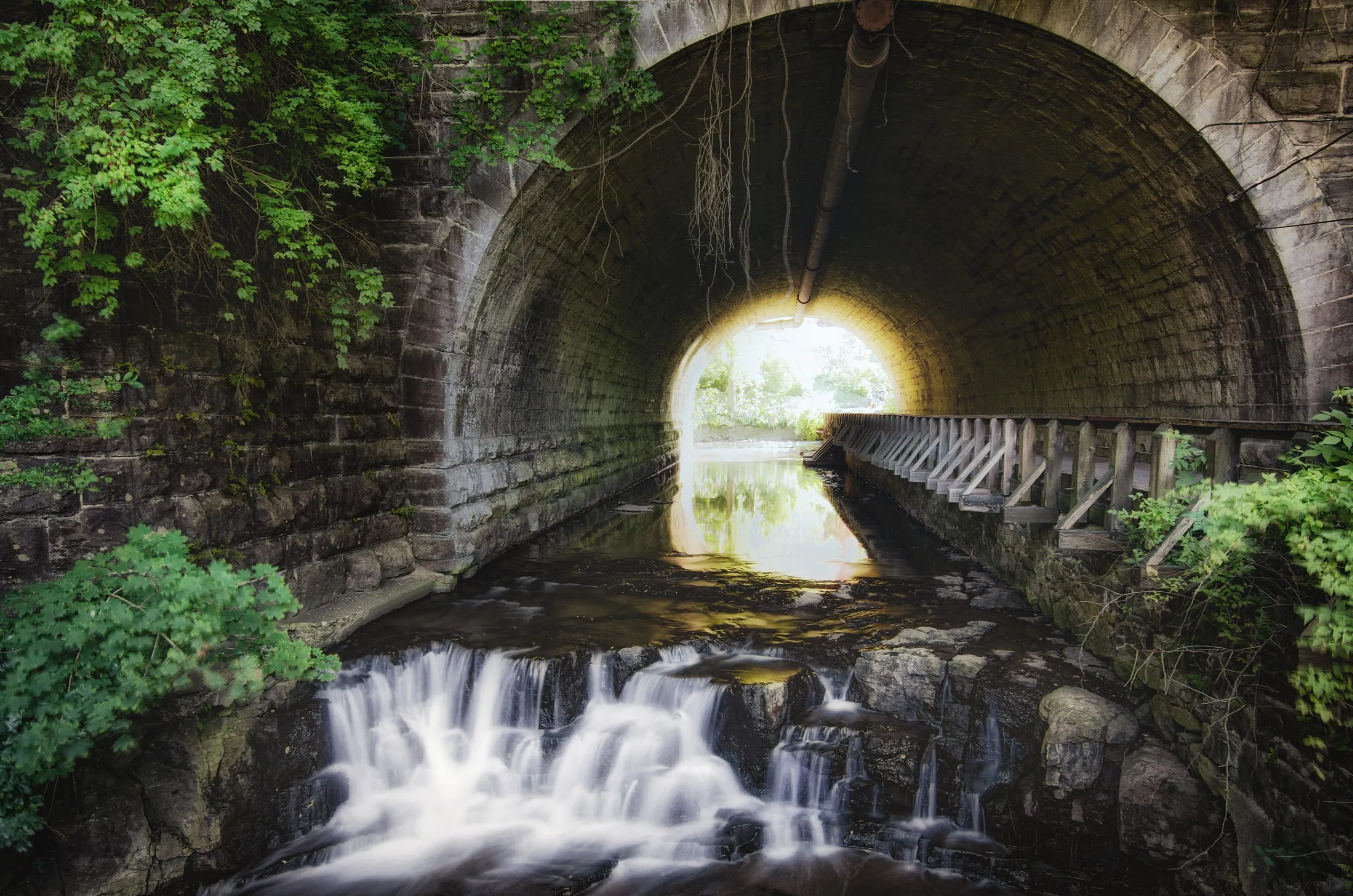 Waterfall seen through a stone tunnel arch in a Rochester glen